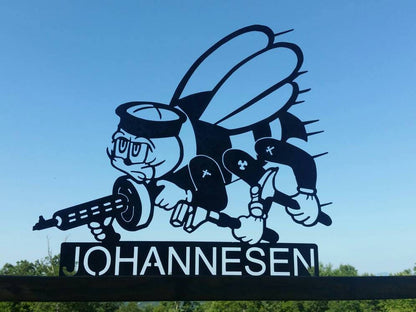 A black metal silhouette of a navy seabee logo wearing a sailor hat and holding a machine gun. The seabee logo has been personalized with a name below the logo.