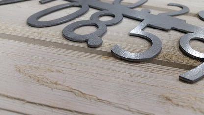 a close up of the metal GPS coordinate sign showing the cut quality and level of detail. the sign is finished in a textured hammered black paint.