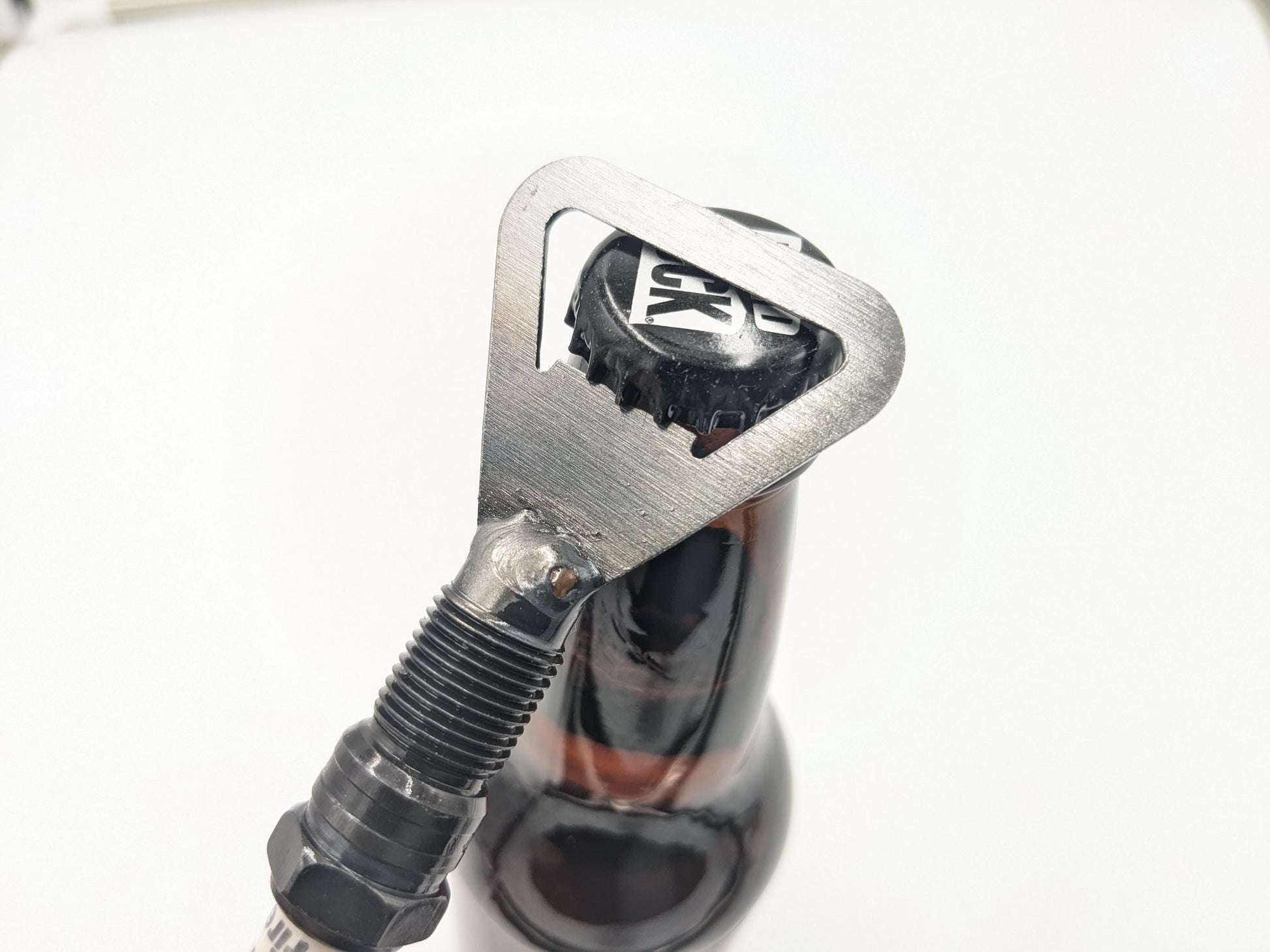 demonstrating how the spark plug bottle opener can be used to open a beer bottle.