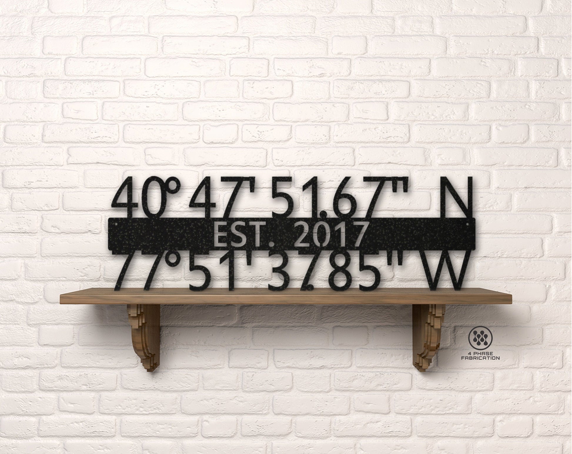 May include: Black metal sign with coordinates 40°47'51.67" N and 77°51'3785" W, EST. 2017. The sign is displayed on a wooden shelf against a white brick wall. The sign is a decorative item.